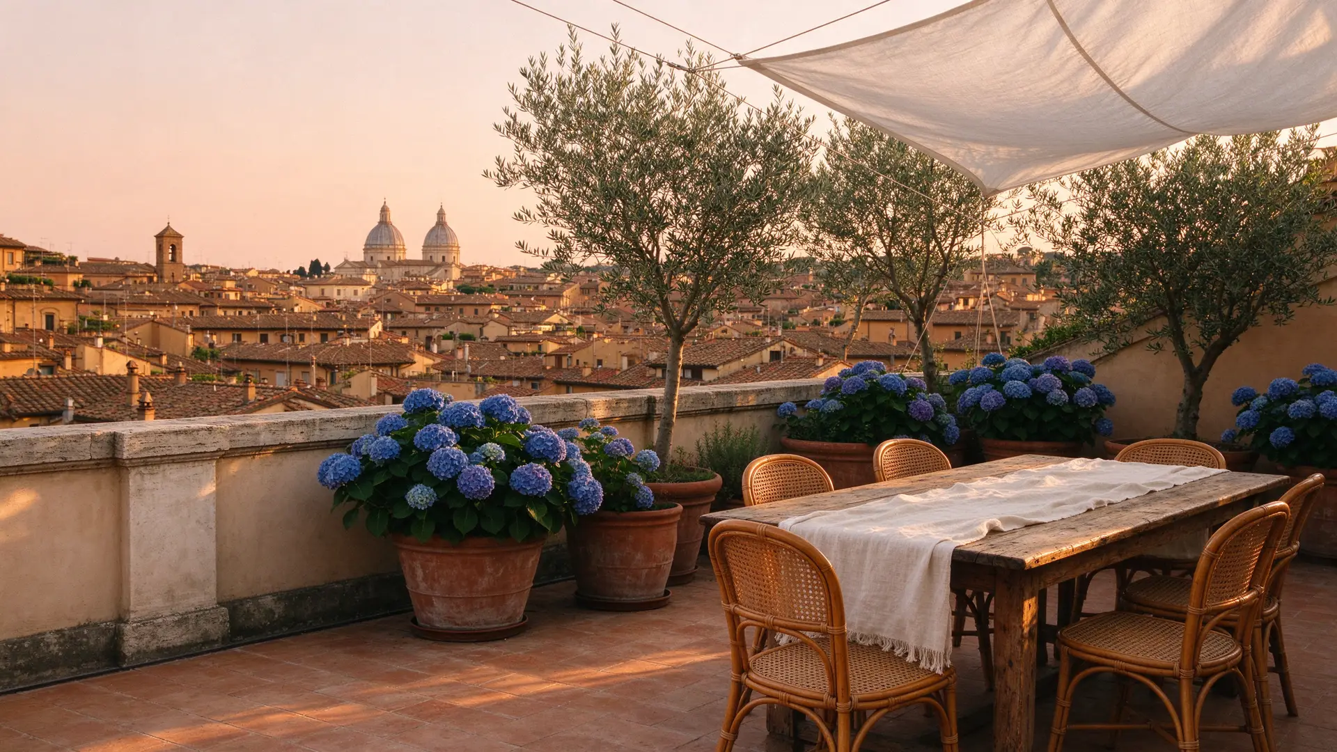 La terrazza sul tetto di Corte Ortensia al tramonto, con le ortensie blu e i tetti di Monti